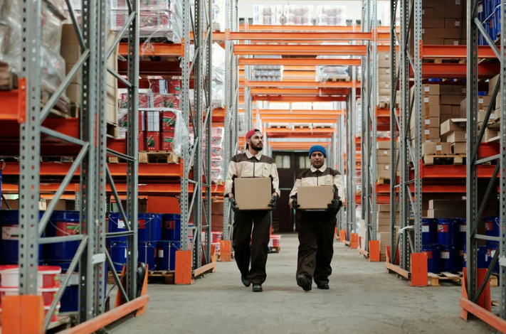 A pair of 3PL workers carrying boxed through a 3PL warehouse.
